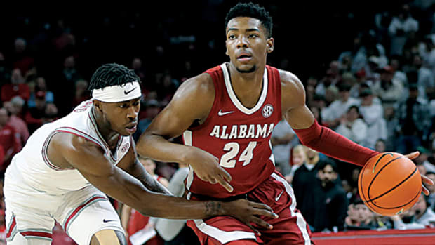 Alabama Crimson Tide forward Brandon Miller dribbles by Arkansas Razorbacks guard Davonte Davis.